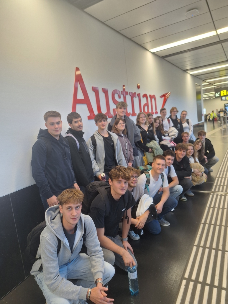 Schülergruppe wartet am Flughafen Wien-Schwechat vor Austrian Airlines Logo